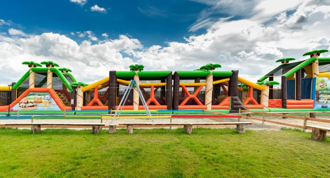 Kolorowy park rozrywki zachodniopomorskie z dmuchanymi zjeżdżalniami i przeszkodami w kształcie dżungli.