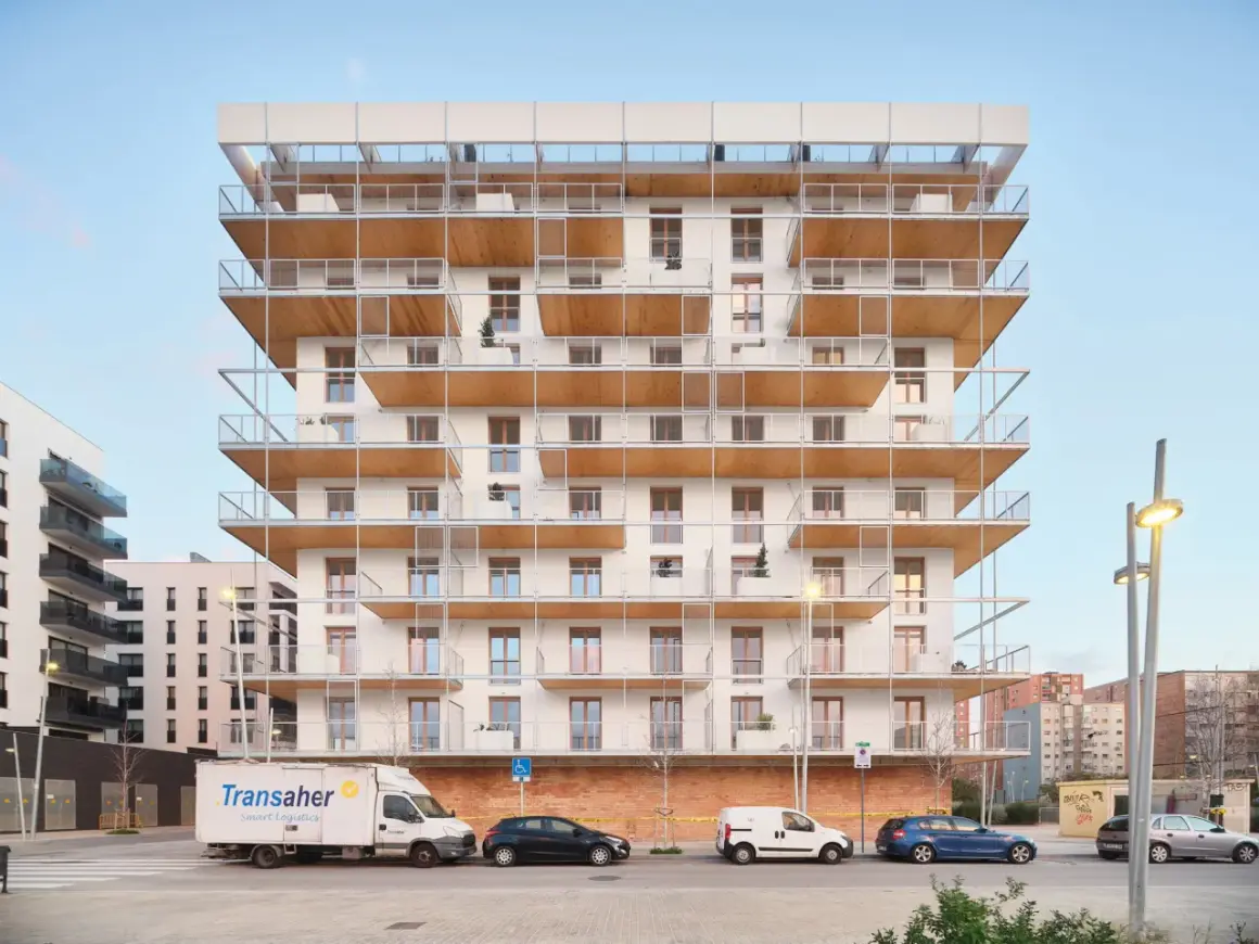 Edificio moderno con balcones de madera y metal. Posiblemente pisos de protección oficial en Barcelona, La Caixa, con vehículos aparcados.
