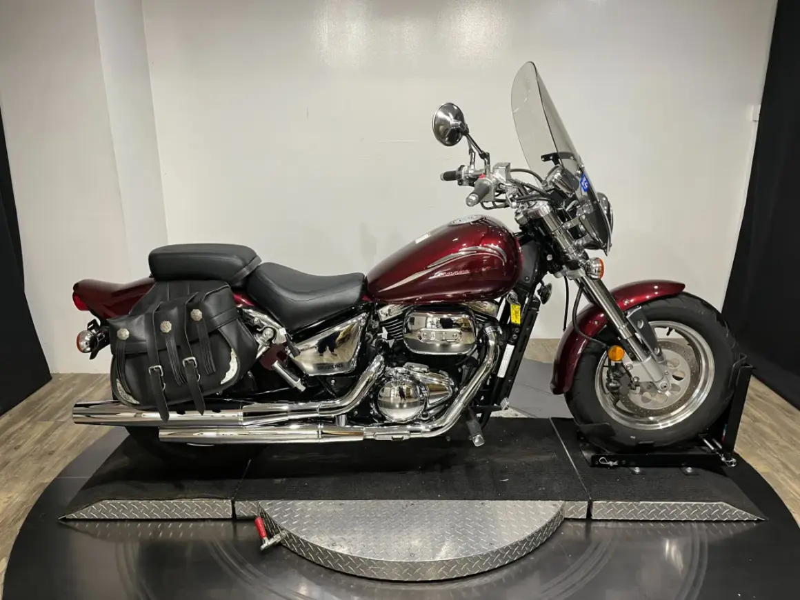 Motocicleta Suzuki Marauder 800 roja con alforjas de cuero y parabrisas.