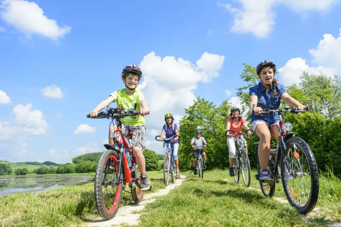 Familie genießt das **Radfahren mit Kindern** auf einem sonnigen Weg am See.