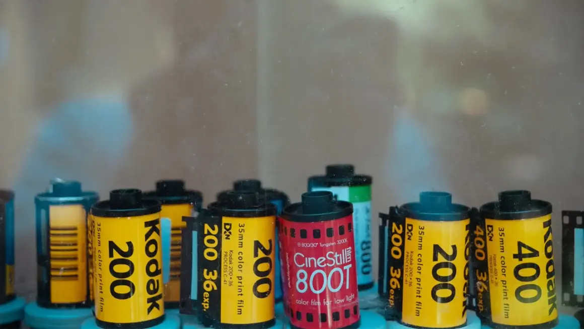 A collection of various types of 35mm film rolls, including Kodak 200, Kodak 400, and CineStill 800T, are displayed.