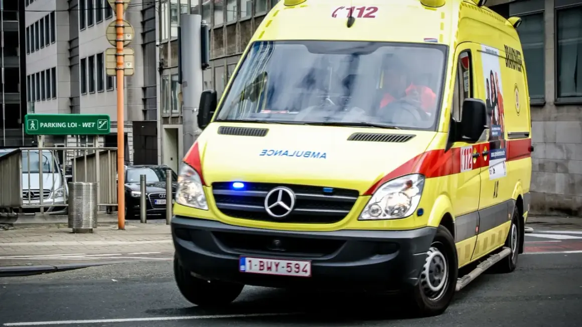 Ambulance jaune, véhicule prioritaire, roule en ville. Les gyrophares bleus clignotent.