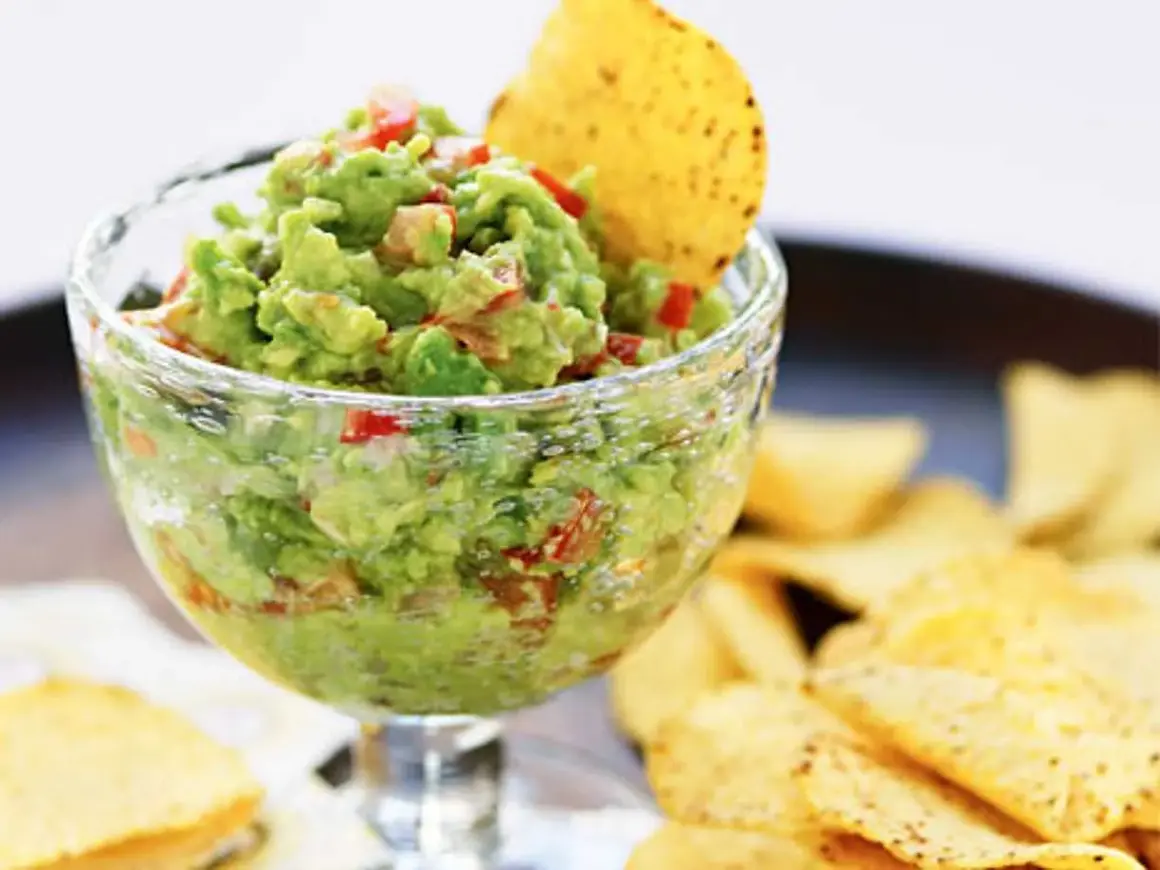 En skål med krämig guacamole, perfekt för ditt nästa guacamole recept. Serveras med tortillachips.