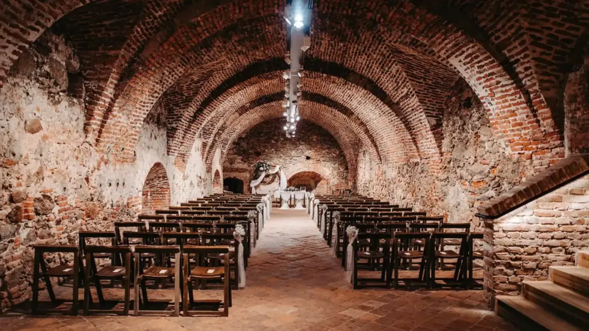 Historische Gewölbe des Kulturvereins Glems, bereit für eine Zeremonie mit Reihen von Holzstühlen und einem festlichen Altar.