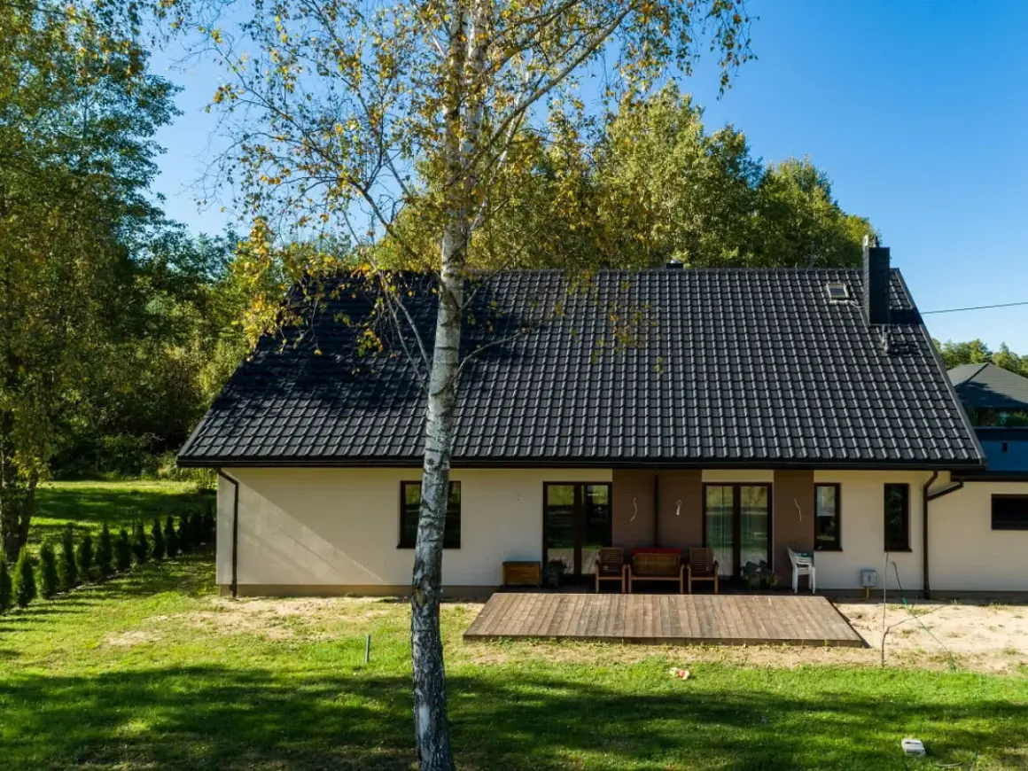 Nowy, czarny dach na domu z tarasem. Zastanawiasz się, jak przedłużyć stary dach? Ten przykład pokazuje, jak odnowić dom.