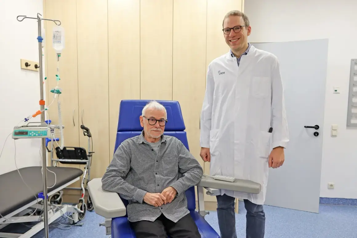 Ein Arzt steht neben einem Patienten, der für eine Alzheimer Behandlung in einem Behandlungsstuhl sitzt. Infusionsständer und medizinische Geräte sind im Hintergrund sichtbar.