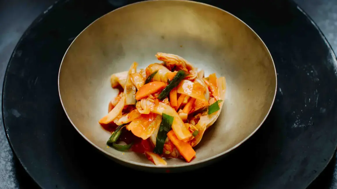 Frisch zubereitetes asiatisches Essen: Kimchi mit Karotten und Frühlingszwiebeln in einer Schüssel.