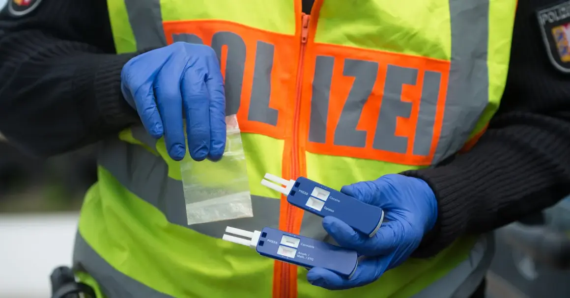 Polizist mit Handschuhen hält Drogenprobe und Tests für Drogen am Steuer.