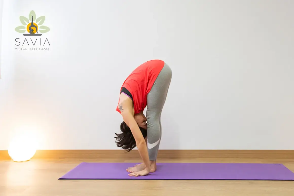 Mujer en postura de Uttanasana yoga, estirando su cuerpo hacia abajo.