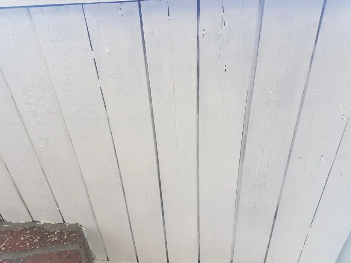 Vitmålad träpanel som takfot, redo för ett nytt lager färg.