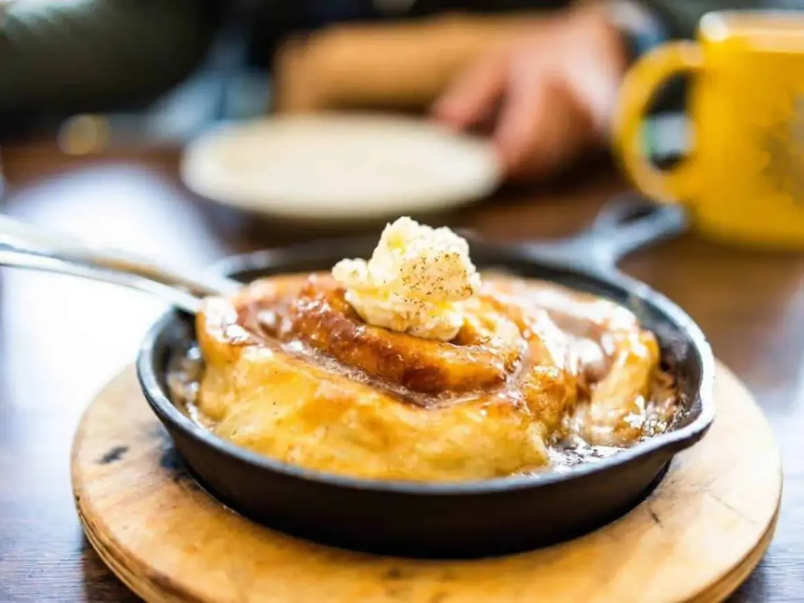 Ein warmer Zimtschnecken-Auflauf in einer Gusseisenpfanne, gekrönt mit Butter. Perfekt, um den Zimtgeschmack zu neutralisieren und den Genuss zu steigern.