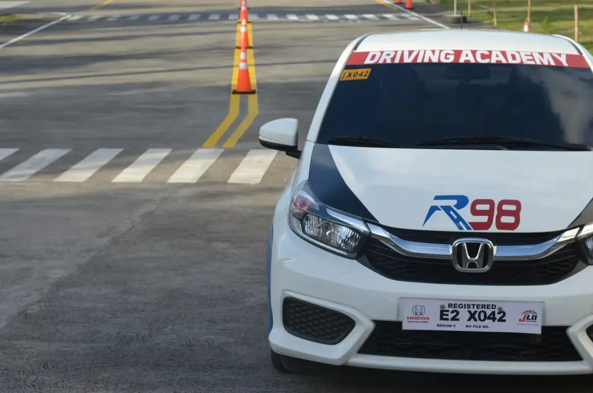 Samochód z napisem "Driving Academy" na placu manewrowym. Może to być miejsce, gdzie można zdobyć prawo jazdy od 16 lat.