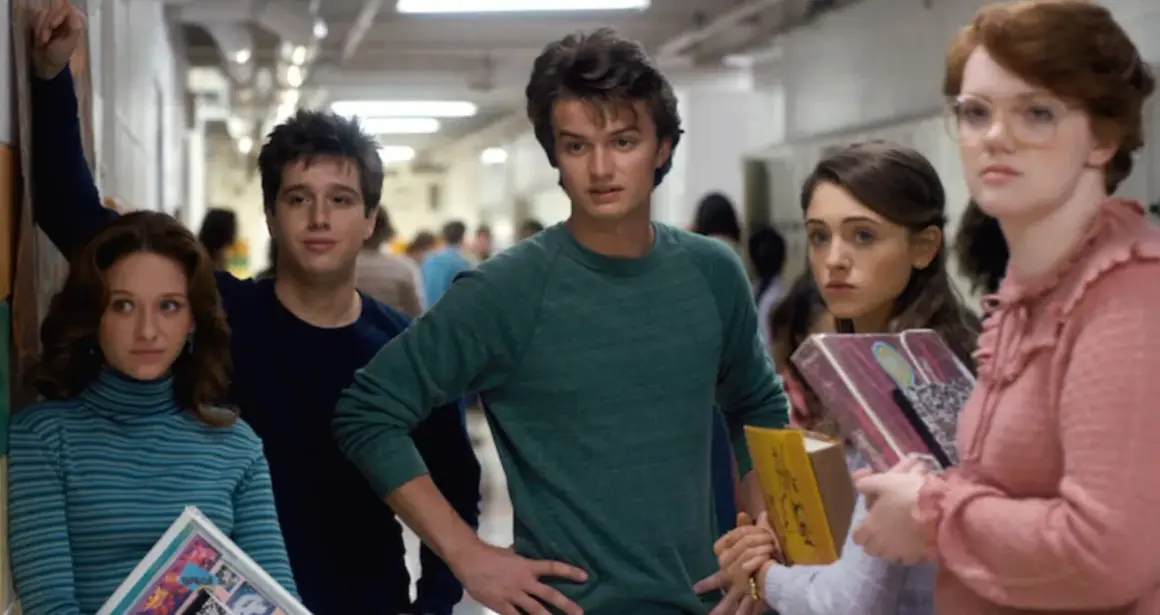 A group of teens in a hallway, featuring the iconic Stranger Things color palette of muted blues, greens, and pinks.