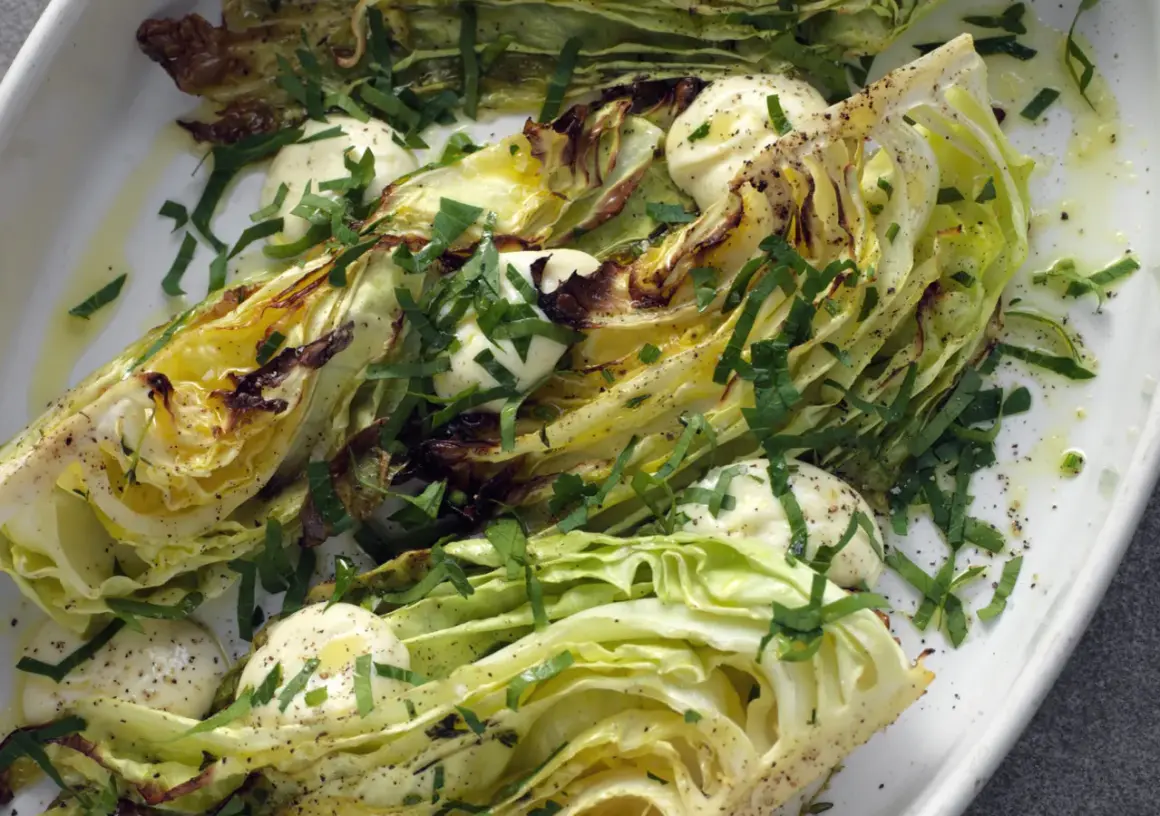 Ugnsbakad vitkål, skuren i klyftor, serverad med en krämig dressing och färska örter. En enkel men smakrik rätt.