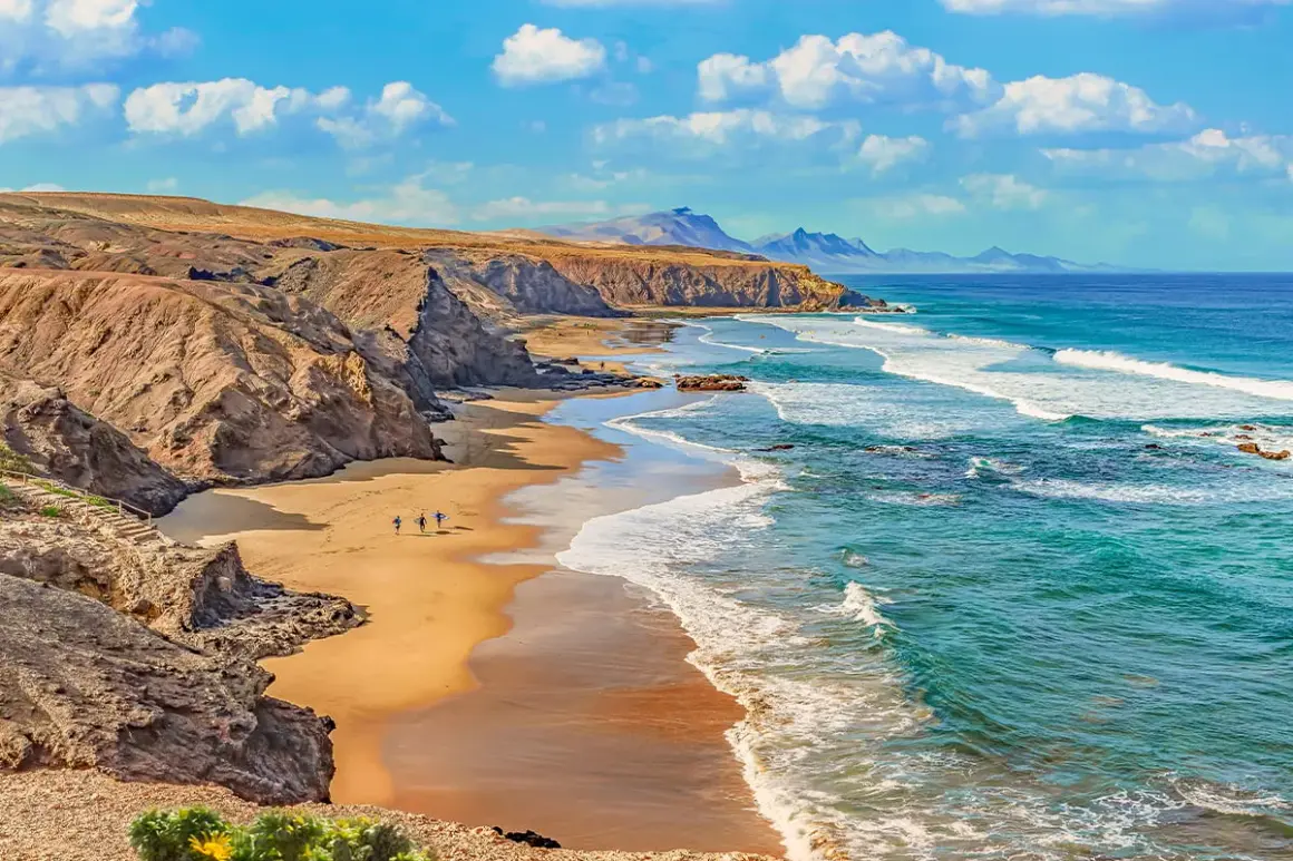 Plaża na Fuerteventurze, gdzie surferzy idą do wody. Tak, Wyspy Kanaryjskie należą do Unii Europejskiej.