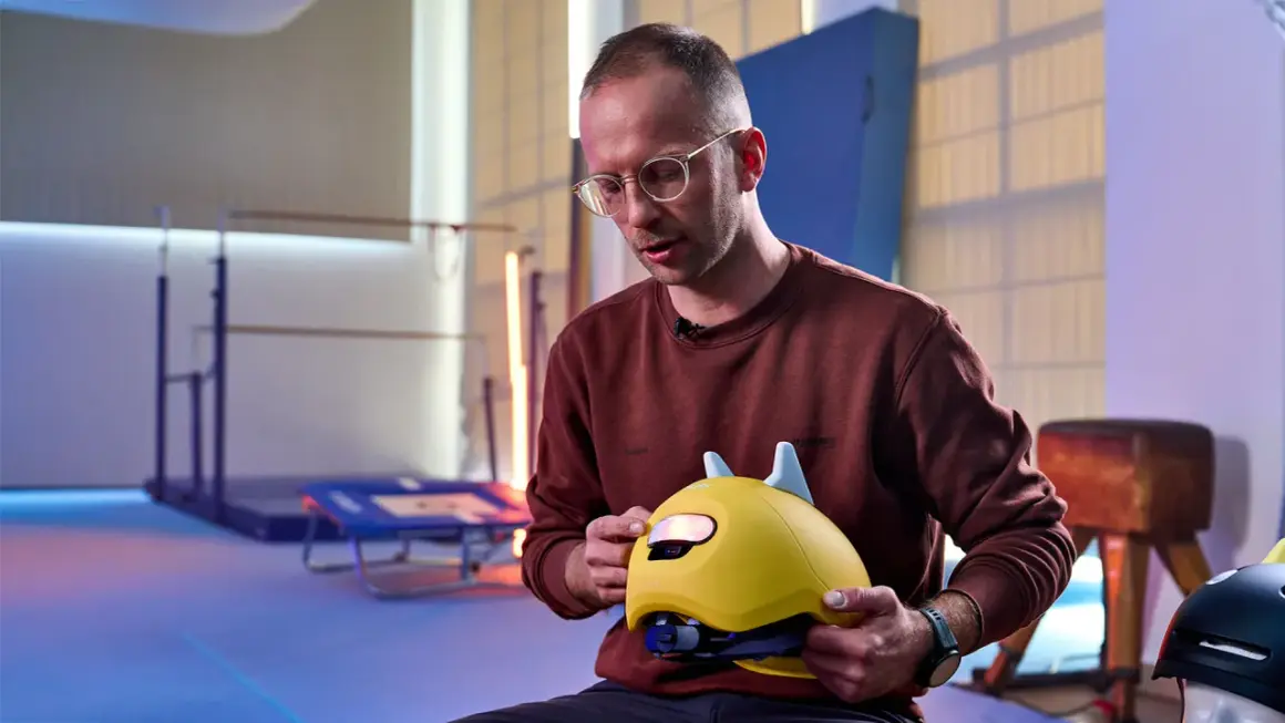 Mann erklärt, wie muss ein Fahrradhelm sitzen: Kinderhelm mit Ohren, gut angepasst und sicher.