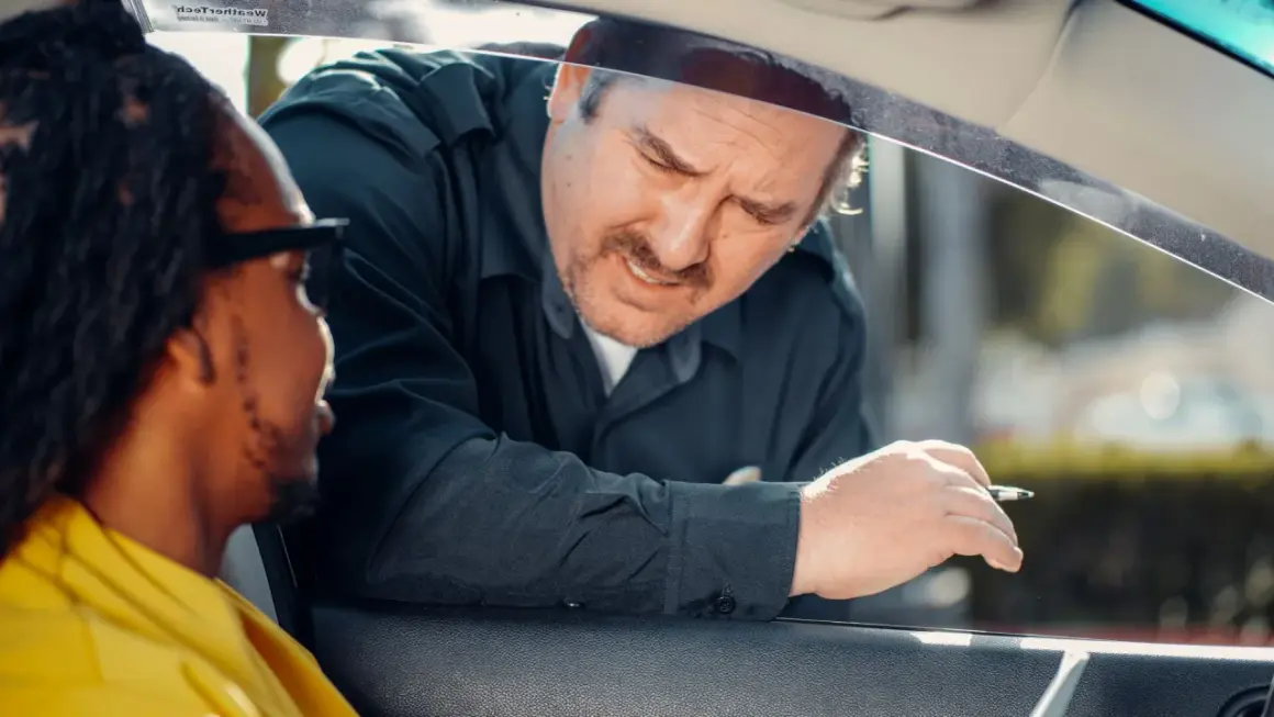 Un policier demande des papiers à un conducteur. Il espère que son nouveau permis de conduire, validité 5 ans, sera en règle.