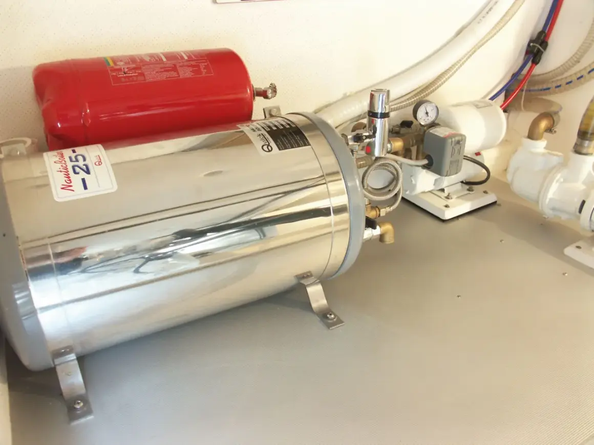 Boiler nautico in acciaio inox e serbatoio rosso. Preparazione per svuotare boiler inverno, con pompe e tubazioni.