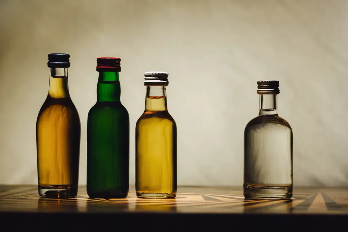 Cztery butelki z płynami: dwie z bursztynowym alkoholem, jedna z zielonym płynem i jedna z przezroczystym. Może to być domowy samogon.