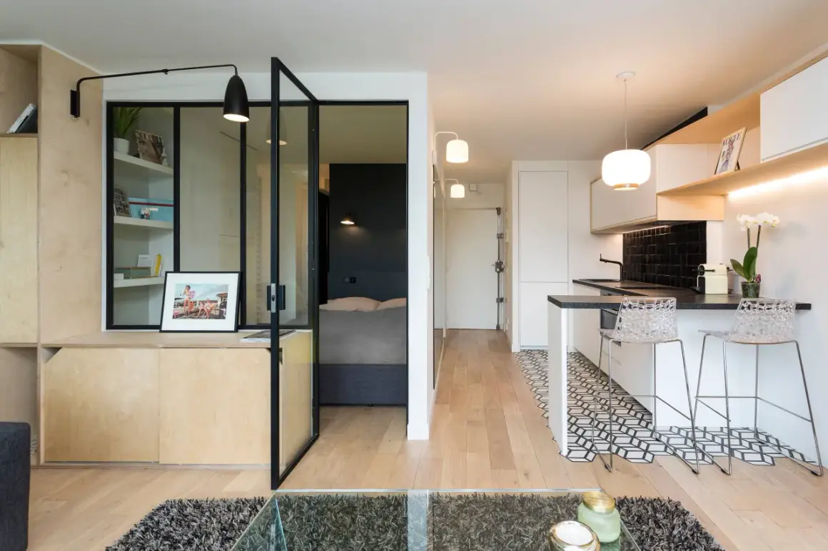 Interno di moderni mini appartamenti con zona giorno, cucina a vista e camera da letto separata da vetrata.