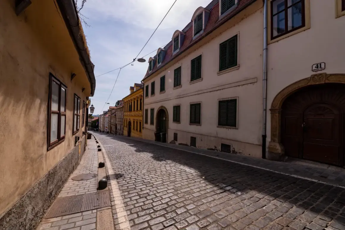 Brukowana uliczka w Zagrzebiu, z kamiennymi domami i latarnią. Odkryj urokliwe zagrzeb atrakcje spacerując tymi uliczkami.