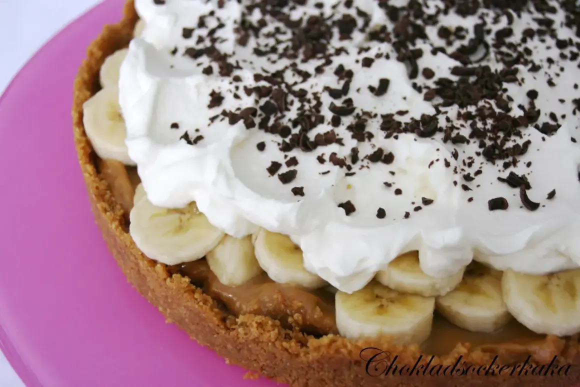 En krämig banoffee paj med lager av banan, kolasås och vispad grädde, toppad med chokladströssel.