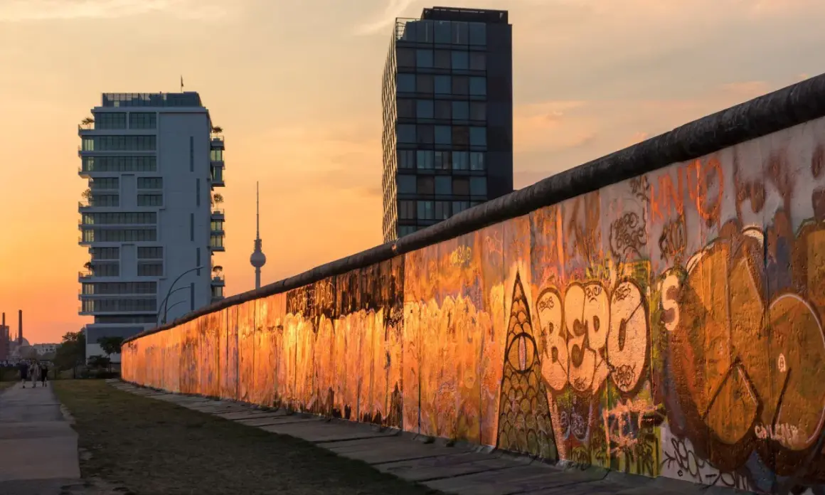 Zachód słońca nad graffiti na pozostałościach Muru Berlińskiego, przypominającego o tym, kiedy został zbudowany mur berliński.
