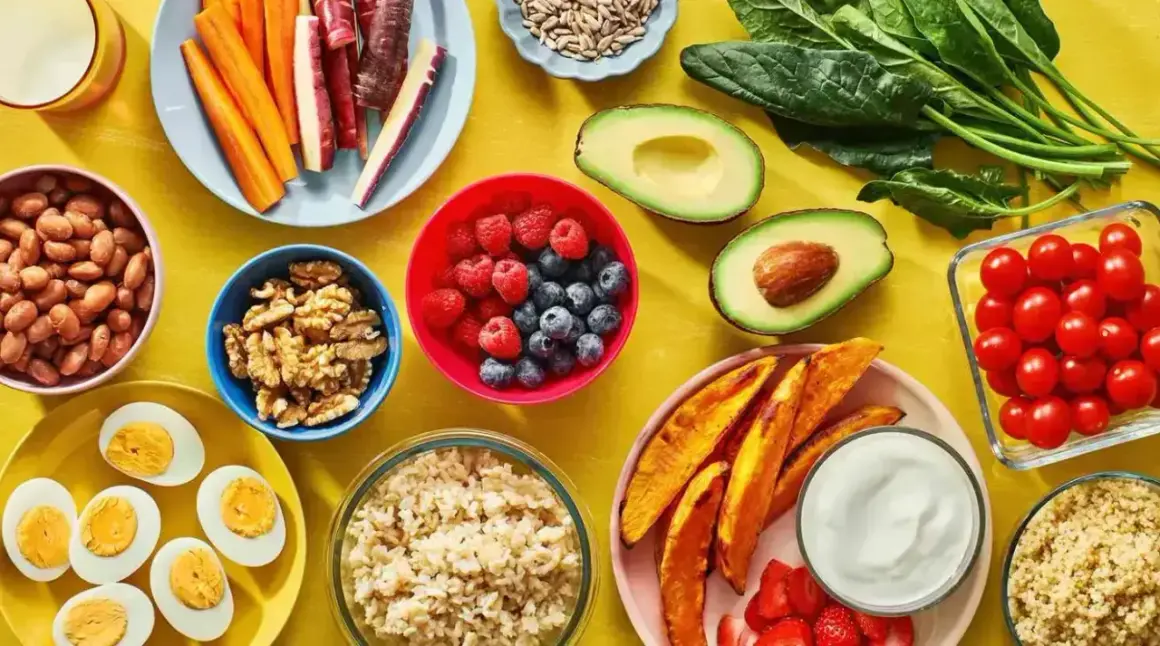 En färgsprakande dukning med proteinrik vegetarisk mat: bönor, ägg, nötter, bär, grönsaker och quinoa.