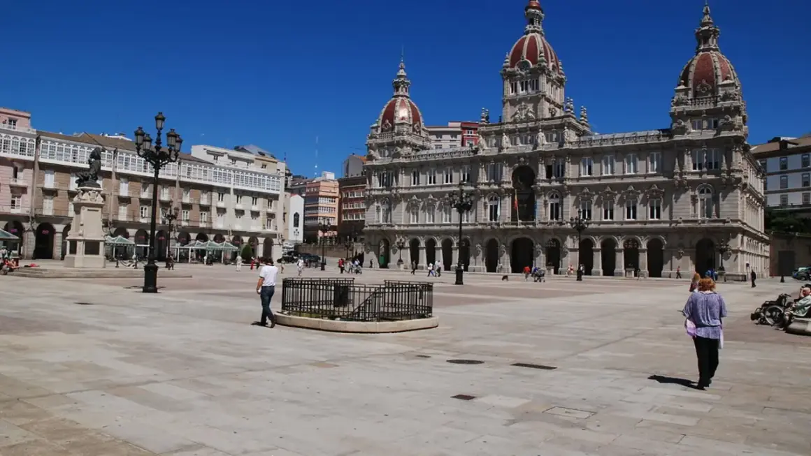 La **plaza María Pita** luce soleada con su ayuntamiento monumental y gente paseando.