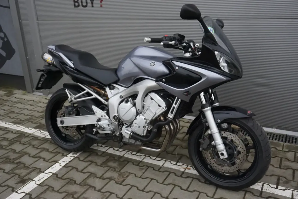 Szary motocykl Yamaha FZ6 z czarnymi akcentami, gotowy do jazdy po miejskich ulicach.