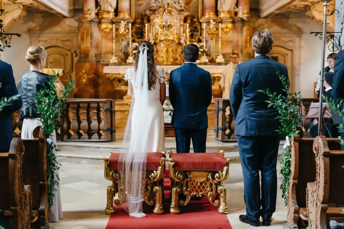 Trauzeugen stehen in der Kirche Spalier. Die Braut und der Bräutigam stehen vor dem Altar.