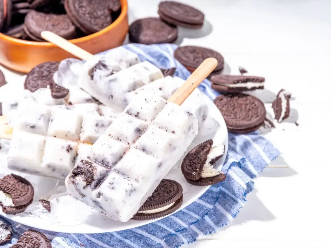 Domowe lody Oreo na patyku, otoczone ciasteczkami Oreo, wyglądają pysznie i orzeźwiająco.