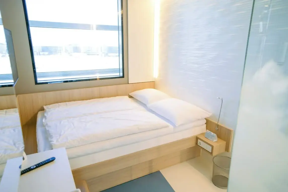 Nowoczesny pokój hotelowy z łóżkiem, oknem i pilotem.