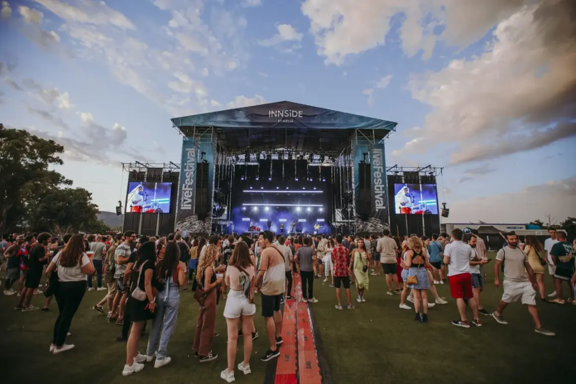 Folla in attesa davanti al palco del Mallorca Live Festival, con schermi giganti che proiettano l'artista.
