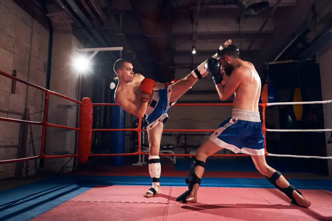 Two men are sparring in a boxing ring, demonstrating that sparring is a sport. One fighter delivers a powerful kick while the other defends.