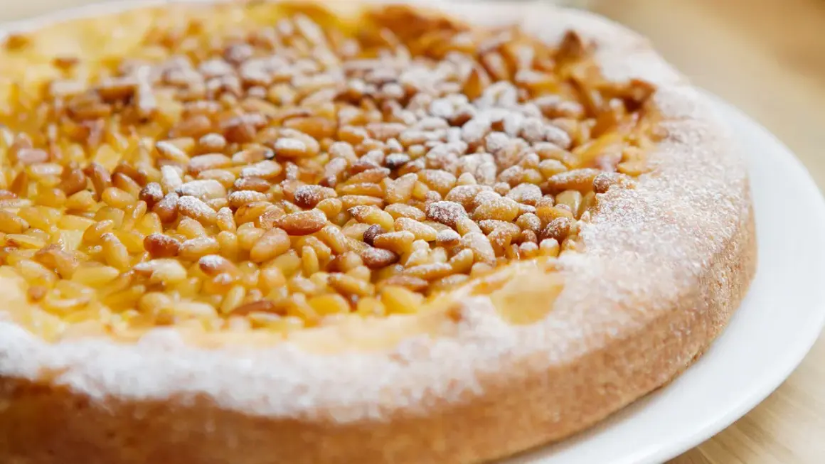 Deliciosa tarta de piñones, cubierta con azúcar glas, lista para disfrutar.