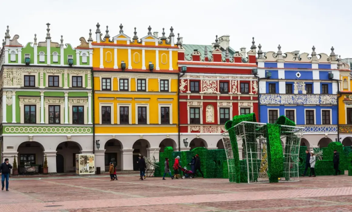 Kolorowe kamienice na Rynku w Zamościu, znane z unikatowych zdobień, tworzą malownicze tło dla świątecznej instalacji w kształcie prezentu.