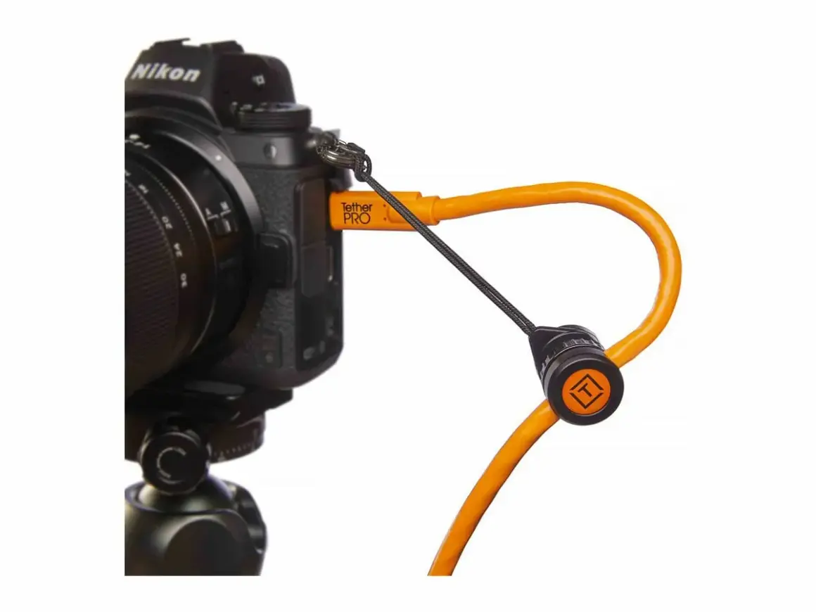 En orange Tether Tools-kabel ansluten till en Nikon-kamera, redo för säker överföring av bilder.