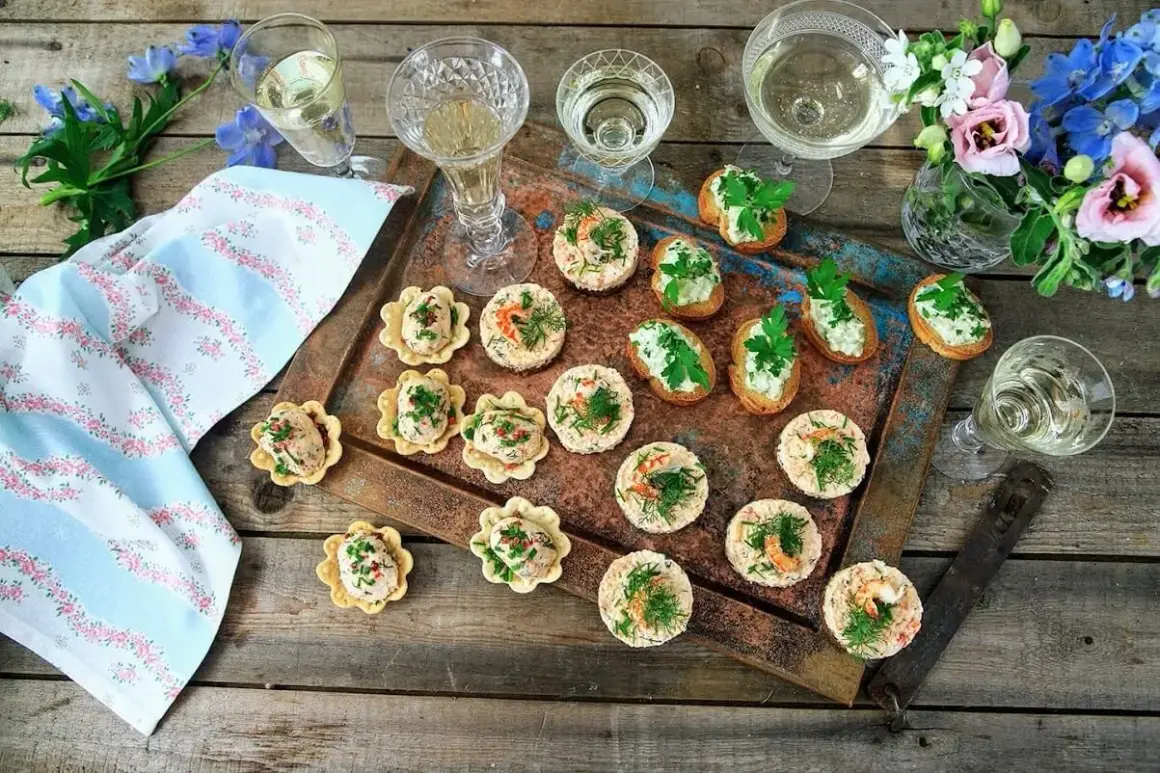 Små, läckra tilltugg till bubbel, serverade på en rustik bricka med blommor och glas. Perfekt för festliga stunder.