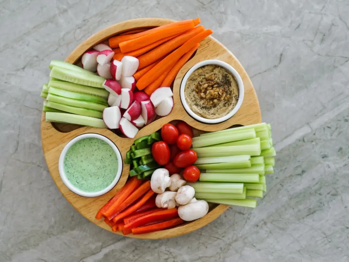 Bunter Gemüseteller mit Hummus und Dip – perfekt für einen 1000 kcal am Tag Essensplan. Karotten, Gurken, Radieschen, Paprika, Tomaten, Sellerie und Pilze.