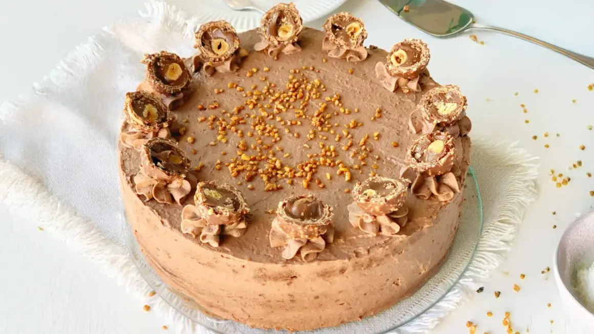 Eine köstliche Rocher Torte mit Schokoladencreme und gehackten Nüssen, dekoriert mit halbierten Rocher Kugeln.