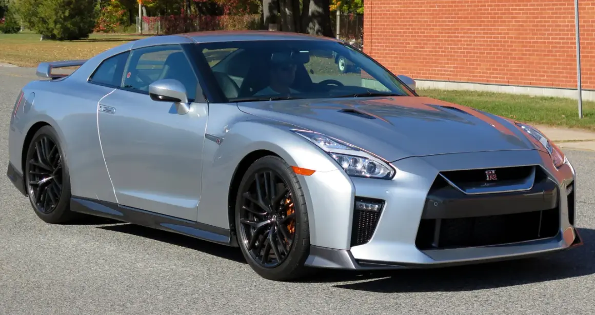 Srebrny Nissan GTR z pomarańczowymi zaciskami hamulcowymi, gotowy do jazdy.