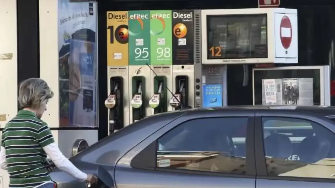 Persona repostando gasolina 95 o 98. El surtidor muestra los precios de los combustibles.
