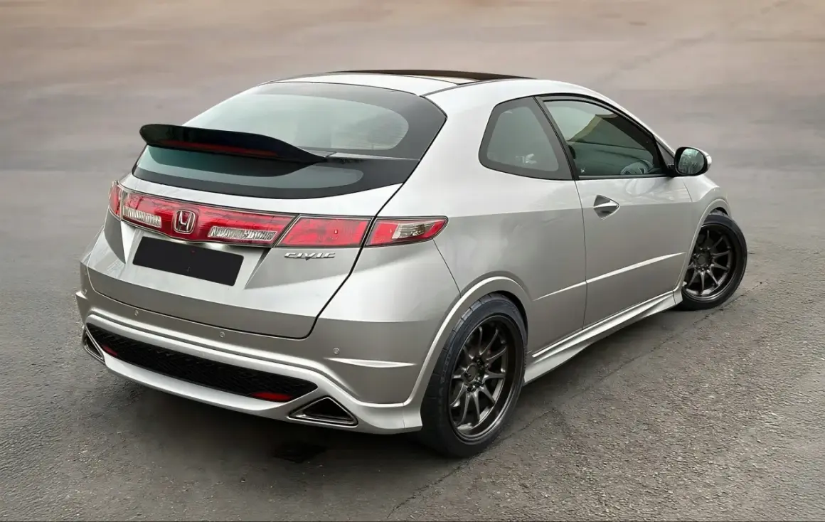 Srebrny Honda Civic VIII z czarnym spoilerem na klapie bagażnika i przyciemnianymi felgami.