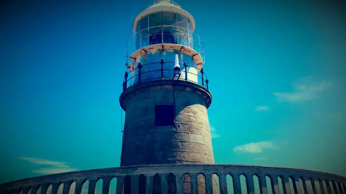 El faro de Corrubedo se alza imponente bajo un cielo azul intenso.