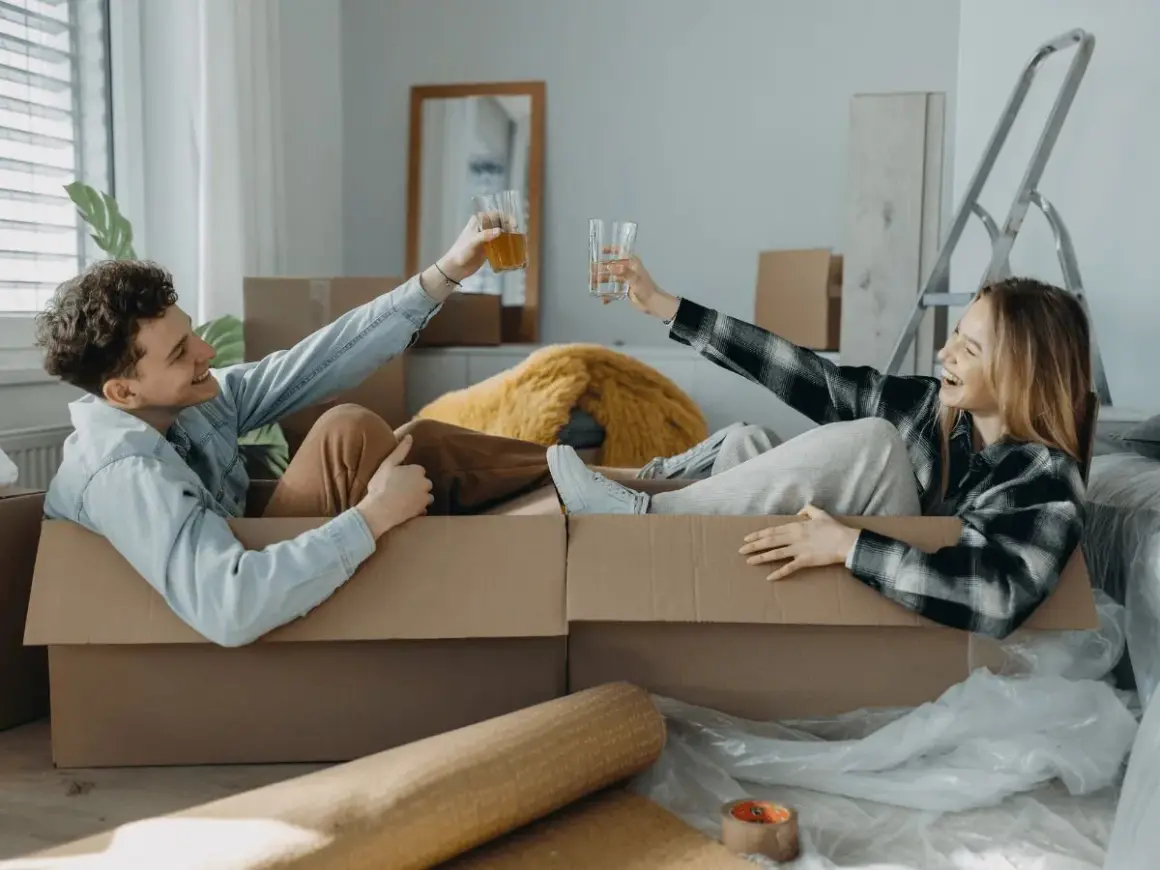 Pareja brindando dentro de cajas, listos para mudarse. ¡Qué alivio que mi casero quiere hacer obras y nos da esta oportunidad!