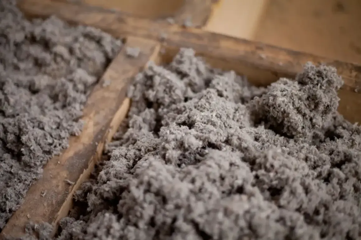 Gros plan sur de la ouate de cellulose grise, un isolant qui peut présenter un danger en cas de mauvaise manipulation.