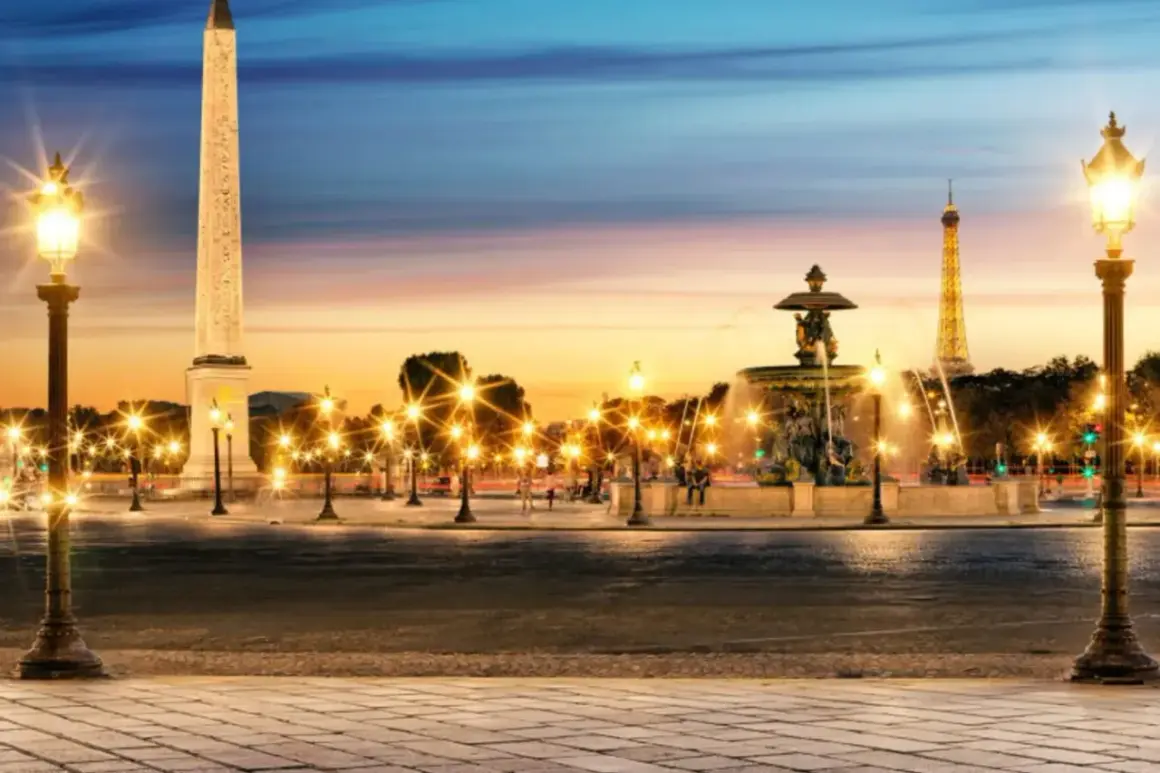 Place de la Concorde i Paris med obelisk, fontän och Eiffeltornet i skymningen. Gatlyktor lyser upp torget.