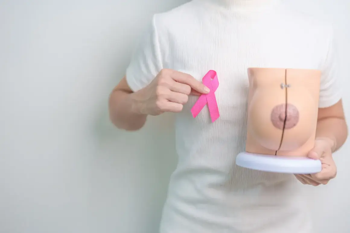 Dłoń trzyma różową wstążkę obok modelu piersi, symbolizując nadzieję po mastektomii z rekonstrukcją.