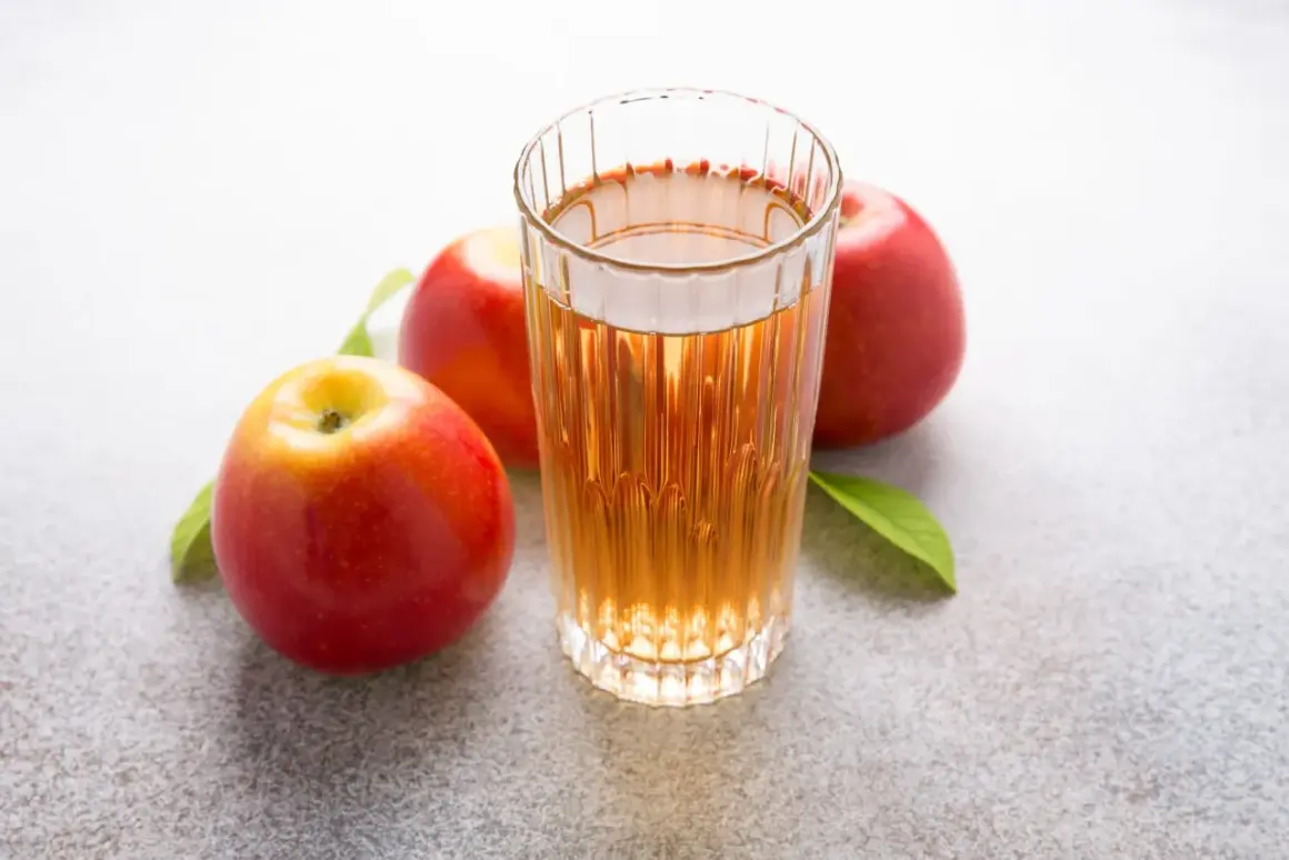 Glas mit Apfelsaft und Äpfeln. Über Apfelessig trinken Nachteile nachdenken.